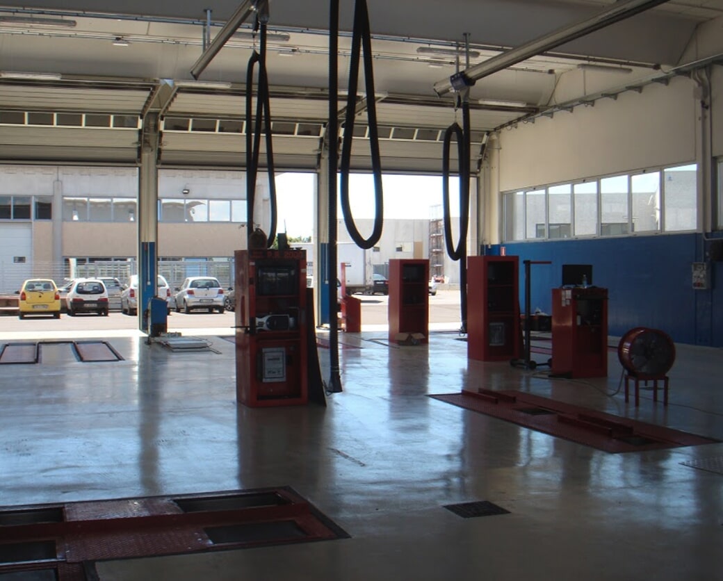 Interno di un'officina meccanica con attrezzature e auto.