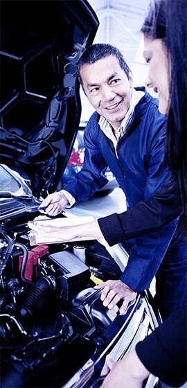 Meccanico e cliente discutono vicino al motore dell'auto.