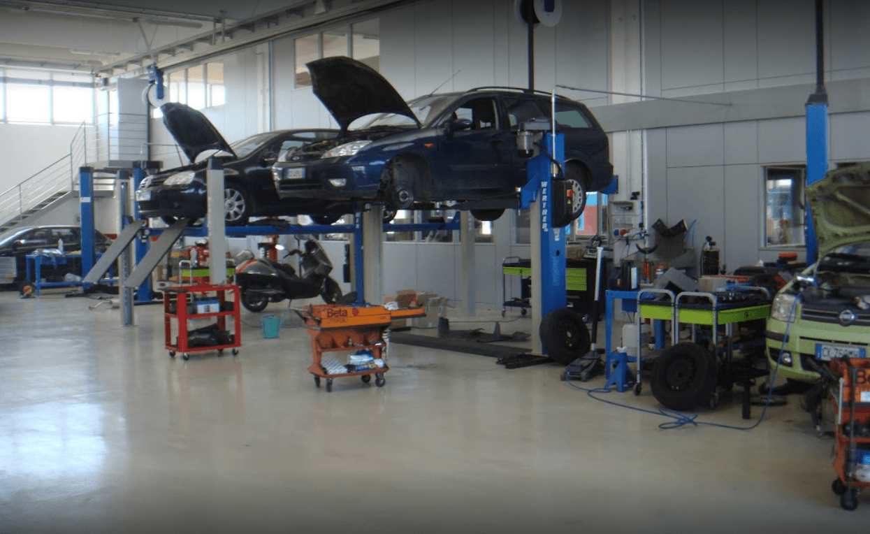 Officina meccanica con auto sollevate e attrezzature.