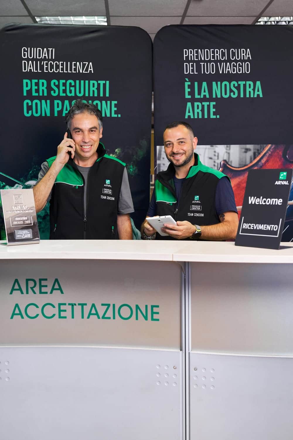 Due uomini sorridenti al banco di accettazione.